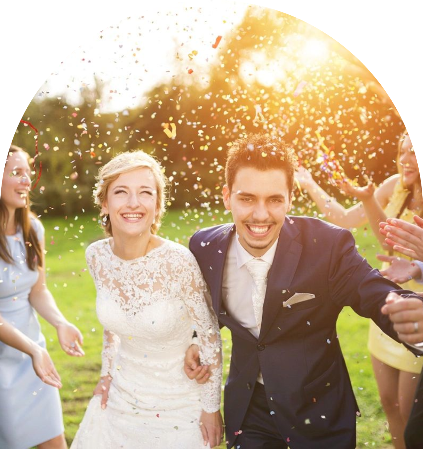 A joyful bride and groom celebrate outdoors with friends throwing confetti.