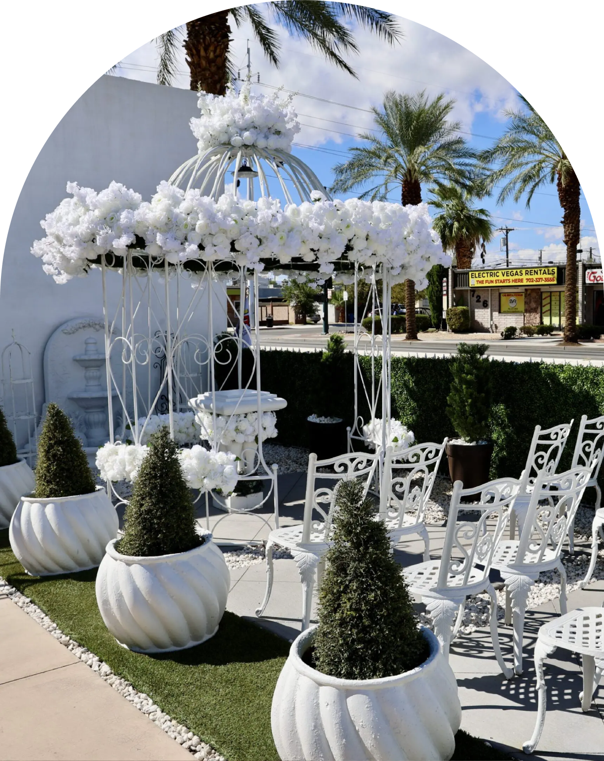 Elegant outdoor wedding setup with white chairs and floral decorations.